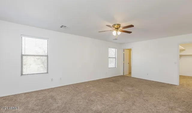 an empty room with windows and chandelier fan