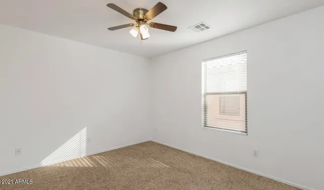 an empty room with windows and fan