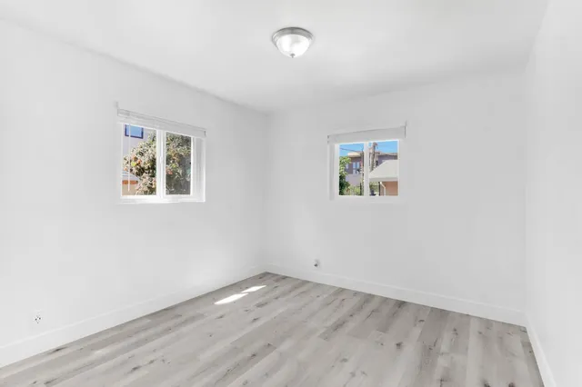 an empty room with wooden floor and window