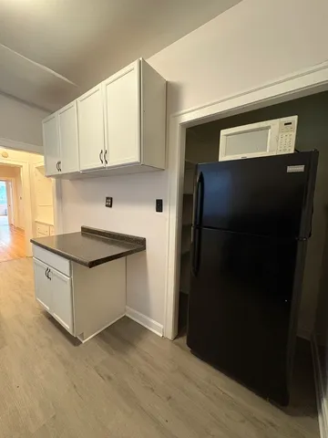 a kitchen with granite countertop white cabinets and refrigerator