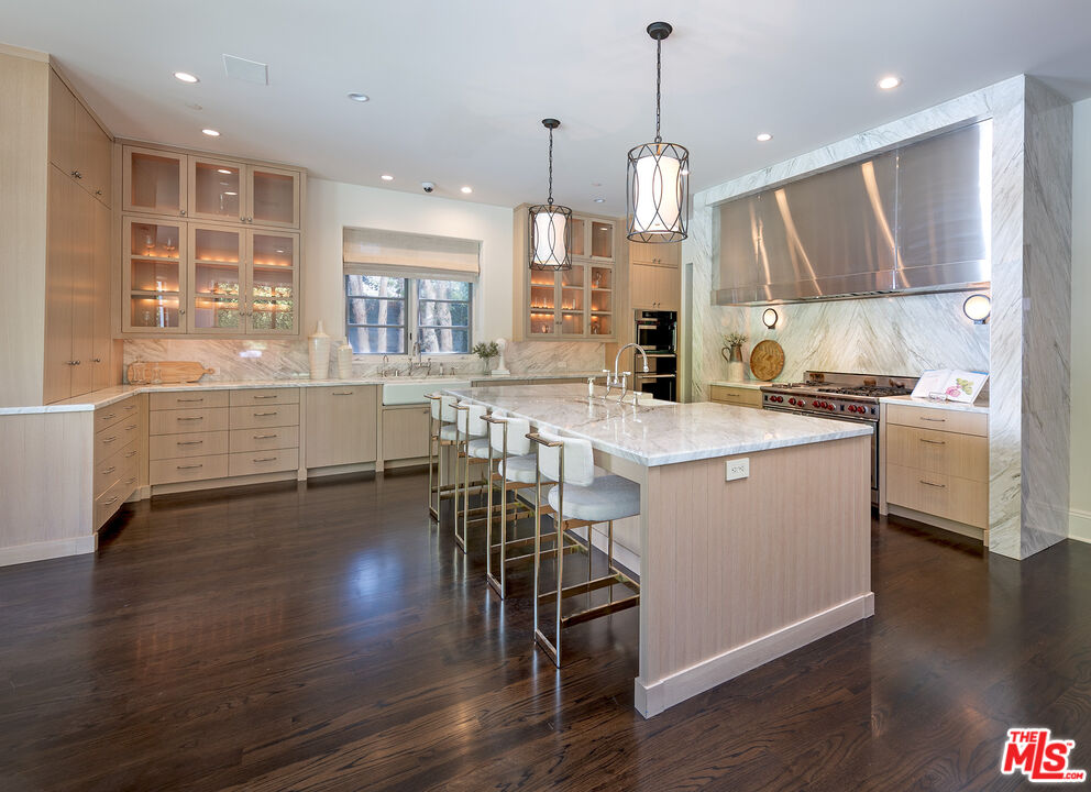 706 North Crescent Drive Beverly Hills, CA 90210 - Photo 16 of 34 a kitchen with stainless steel appliances kitchen island granite countertop a stove a sink a refrigerator and a dining table with wooden floor