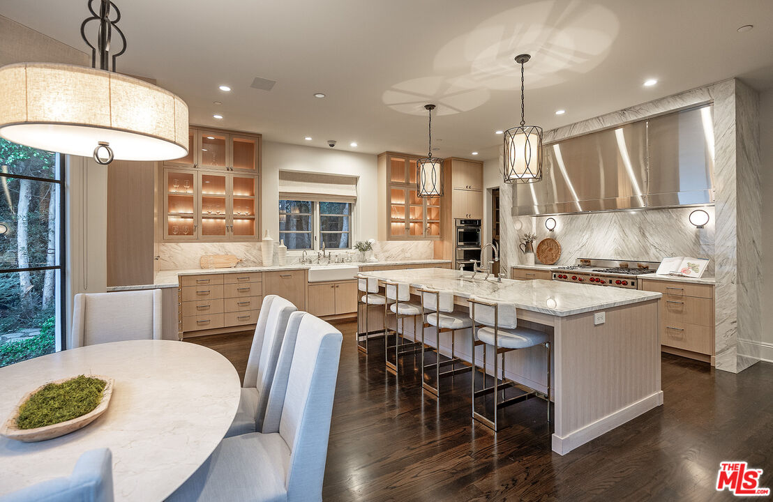 706 North Crescent Drive Beverly Hills, CA 90210 - Photo 32 of 34 a kitchen with stainless steel appliances granite countertop a stove a sink a kitchen island and chairs with wooden floor