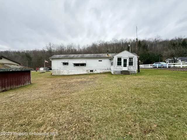 a view of a house with a big yard and large trees