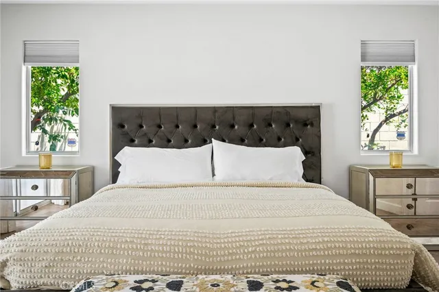 a large white bed in a bedroom next to a window