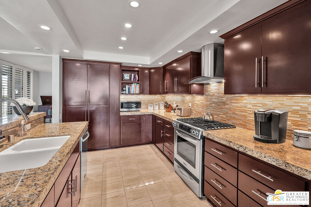 72355 Rodeo Way Rancho Mirage, CA 92270 - Photo 16 of 43 a kitchen with stainless steel appliances granite countertop a sink counter space cabinets and a large window