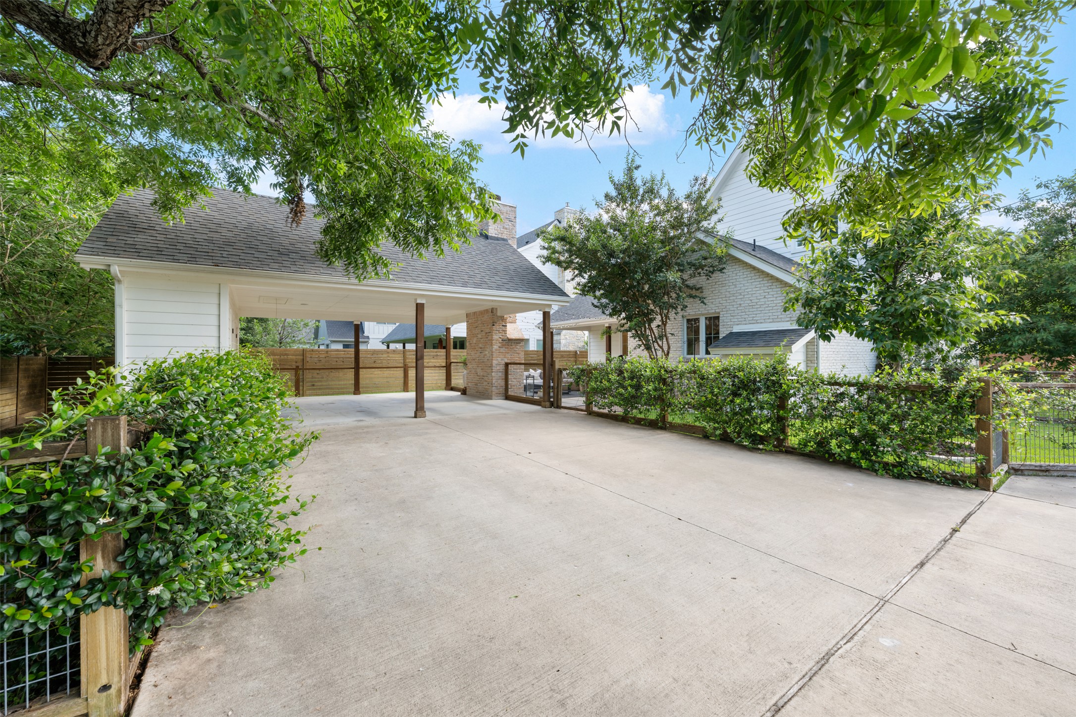 1301 West Street Georgetown, TX 78626 - Photo 40 of 40 A spacious concrete driveway leads to a covered carport, flanked by mature landscaping and a privacy fence.
