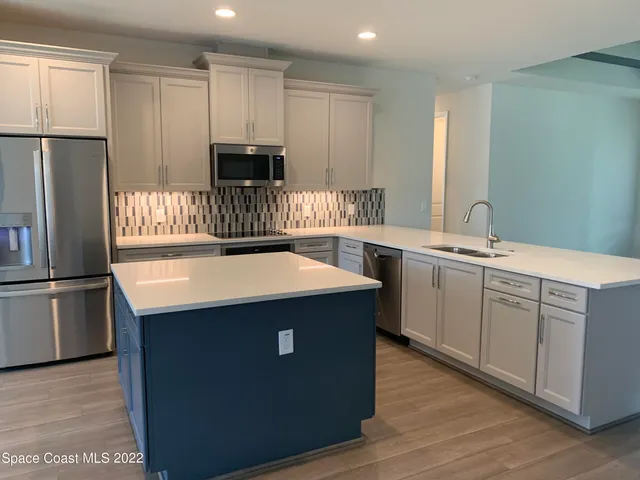 a kitchen with stainless steel appliances a sink a stove a refrigerator and cabinets