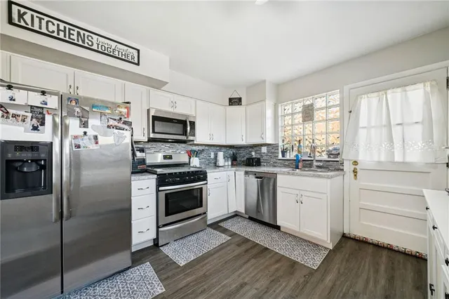 a kitchen with granite countertop stainless steel appliances cabinets and a wooden floor