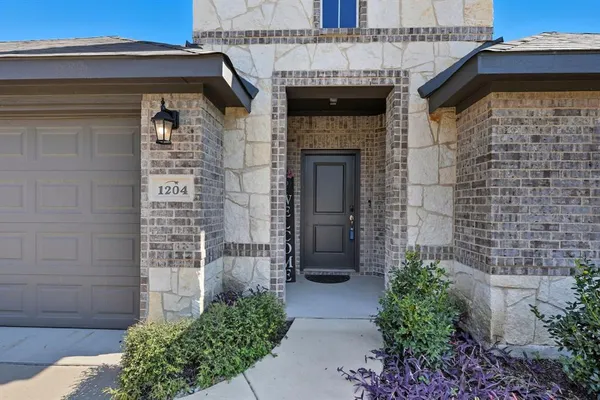 a stone house with potted plants in front of door