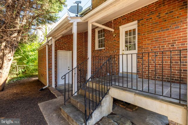 a view of backyard with brick wall and a large tree