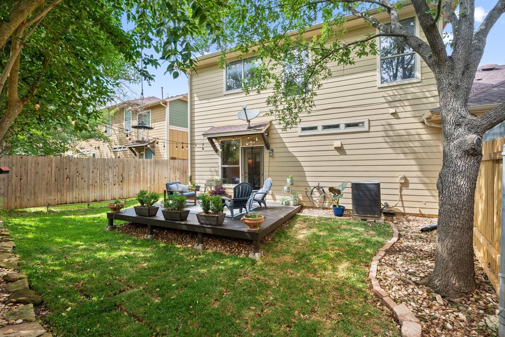6708 Menchaca Road, Unit 2 Austin, TX 78745 - Photo 28 of 30 Expansive backyard featuring a raised wood deck, privacy fencing, mature trees, and a manicured lawn