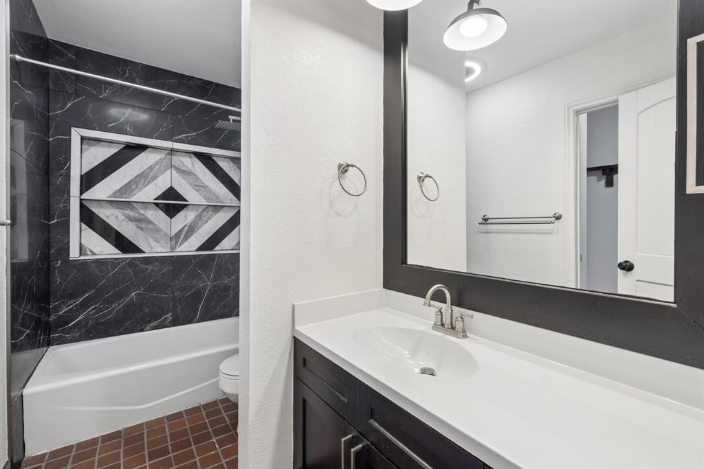 15539 Preston Road, Unit 1037 Dallas, TX 75248 - Photo 16 of 36 Bathroom featuring a dark wood-finish vanity with a single basin sink, a framed mirror, and a white countertop