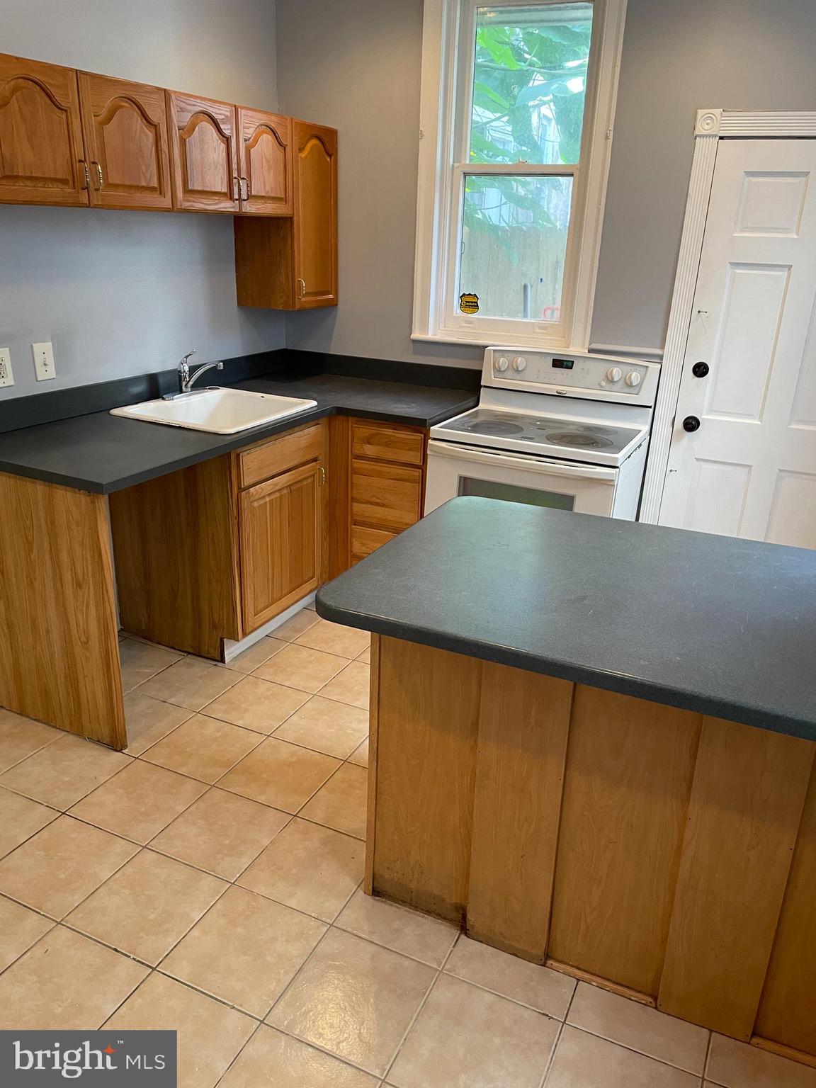 a kitchen with kitchen island granite countertop a sink cabinets and window