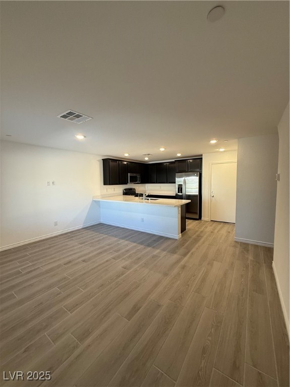 10774 Astell Isle Court Las Vegas, NV 89166 - Photo 33 of 34 Kitchen featuring a peninsula, dark cabinets, recessed lighting, open floor plan, and light wood-style flooring