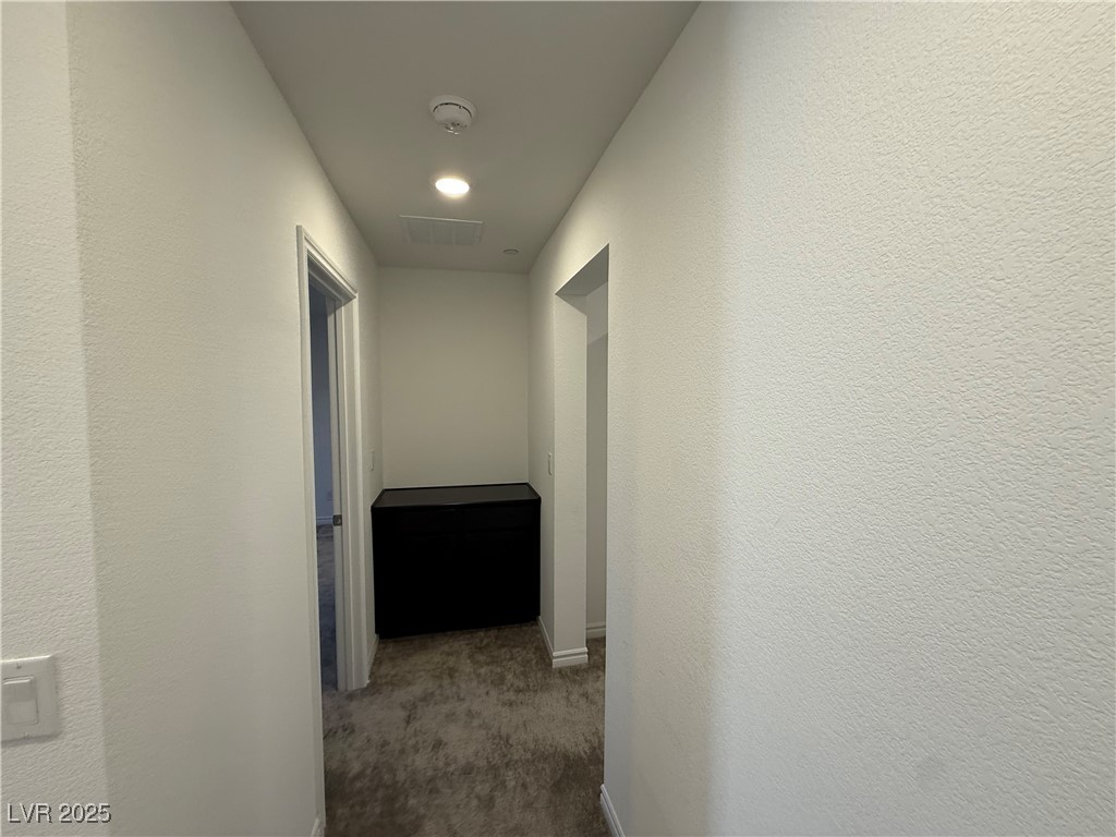 10774 Astell Isle Court Las Vegas, NV 89166 - Photo 15 of 34 Corridor featuring dark colored carpet and a textured wall