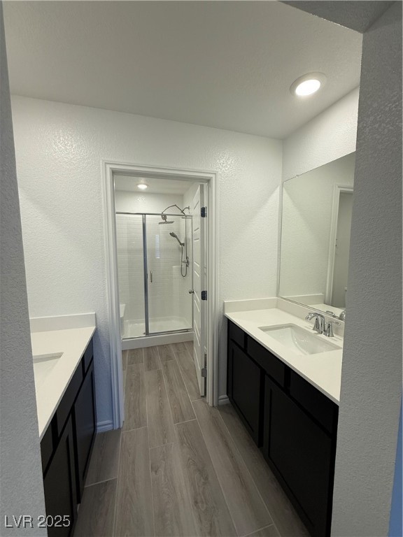 10774 Astell Isle Court Las Vegas, NV 89166 - Photo 20 of 34 Full bathroom with wood tiled floors, a textured wall, a stall shower, and two vanities