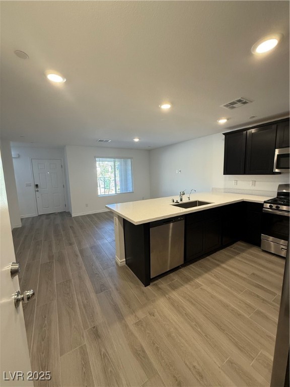 10774 Astell Isle Court Las Vegas, NV 89166 - Photo 6 of 34 Kitchen featuring dark cabinetry, light wood finished floors, range, dishwashing machine, and recessed lighting