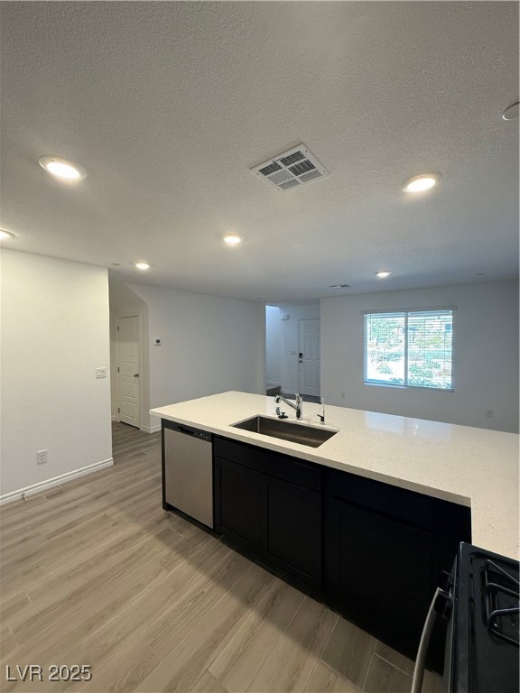 10774 Astell Isle Court Las Vegas, NV 89166 - Photo 8 of 34 Kitchen with dark cabinetry, light wood-type flooring, range, dishwasher, and light stone countertops