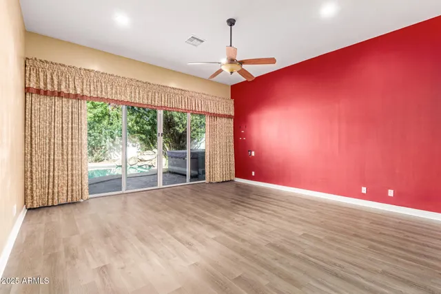 a view of empty room with wooden floor and fan