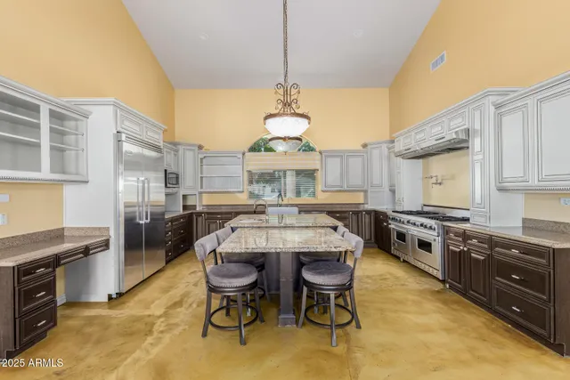 a kitchen with stainless steel appliances granite countertop a stove a sink dishwasher a dining table and chairs with wooden floor