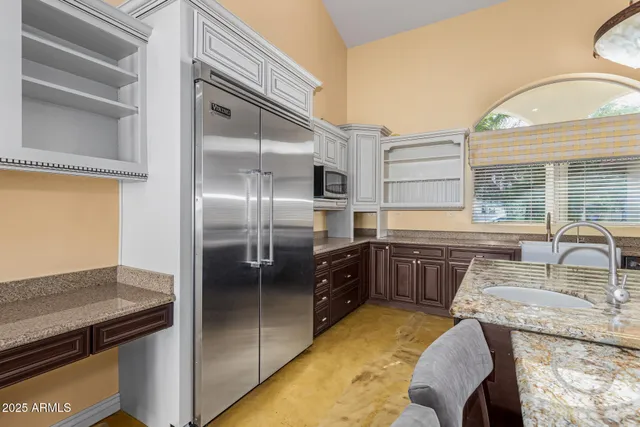 a kitchen with stainless steel appliances granite countertop a sink and a refrigerator