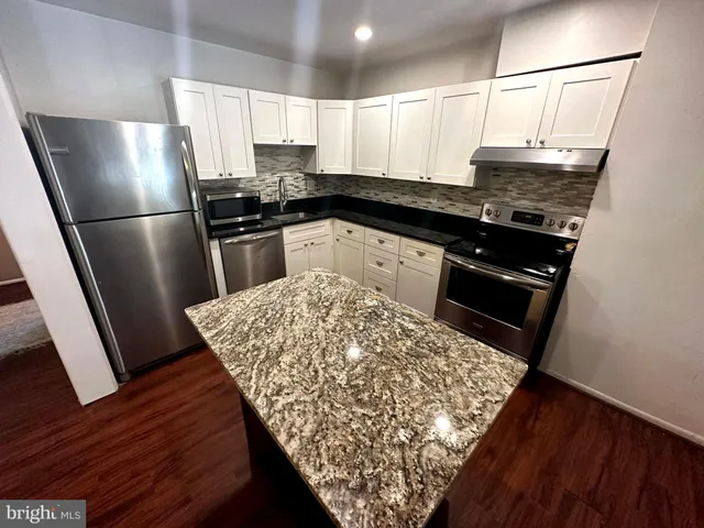 a kitchen with stainless steel appliances granite countertop a refrigerator sink and stove