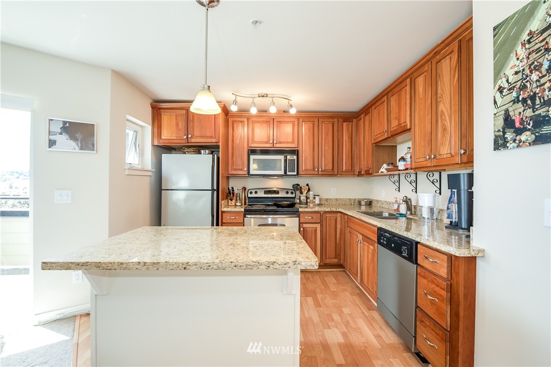 3232 15th Avenue West Seattle, WA 98119 - Photo 12 of 18 a kitchen with granite countertop a refrigerator a sink dishwasher a stove and a oven with wooden floor