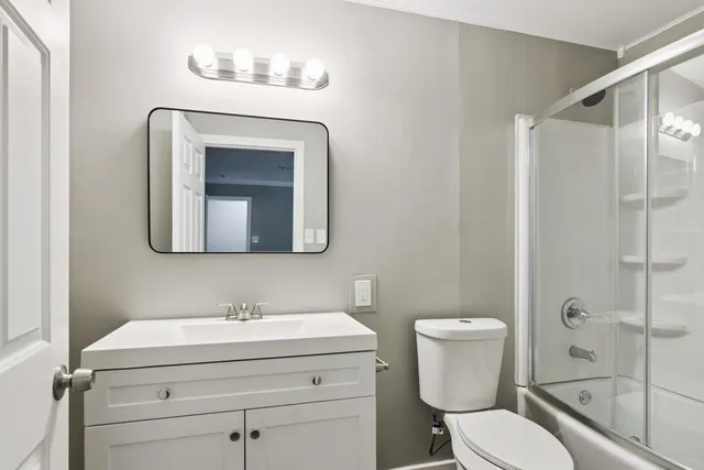 a bathroom with a toilet sink vanity and mirror