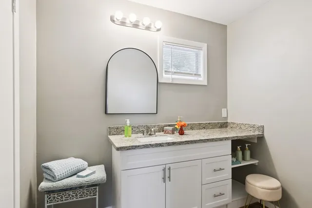 a bathroom with a granite countertop toilet sink and mirror