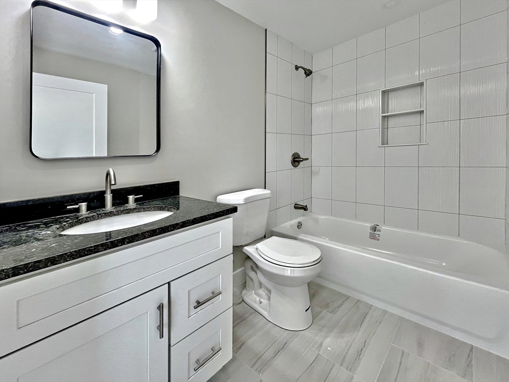 14 Dyer Street, Unit 14 Rockland, MA 02370 - Photo 4 of 16 a bathroom with a toilet a sink a mirror and bathtub