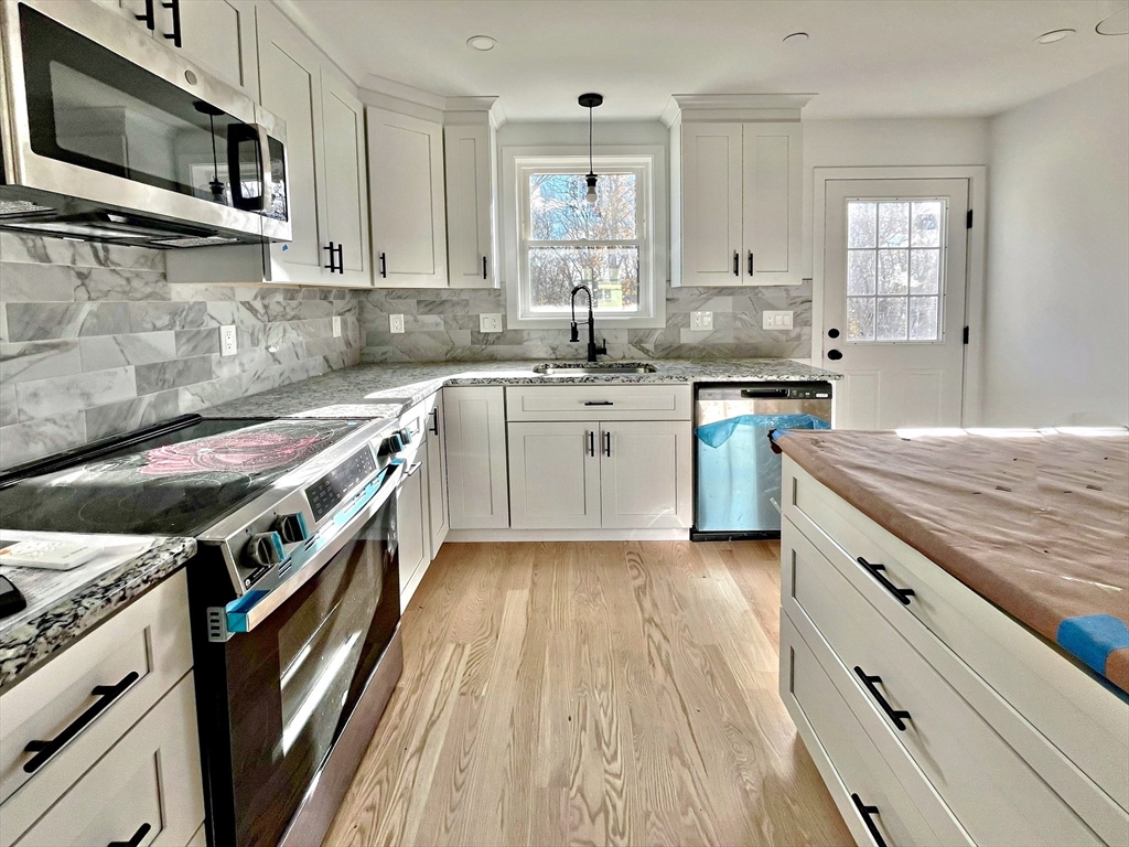14 Dyer Street, Unit 14 Rockland, MA 02370 - Photo 5 of 16 a kitchen with stainless steel appliances granite countertop a stove top oven a sink dishwasher and a microwave oven with large wooden cabinets