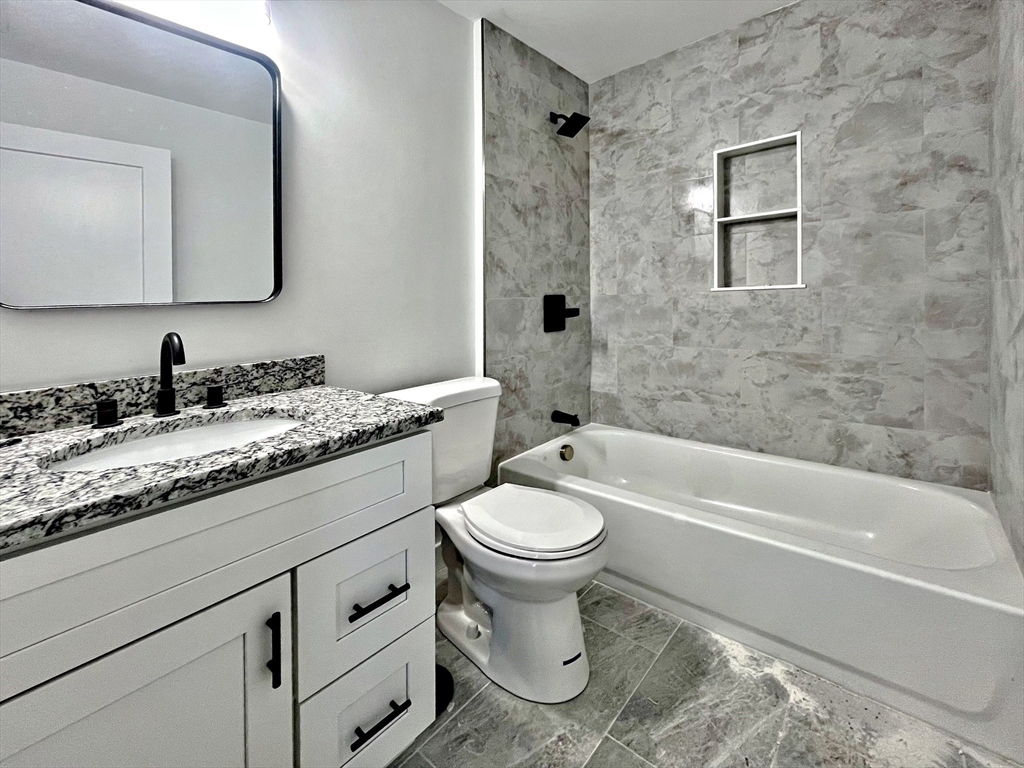 14 Dyer Street, Unit 14 Rockland, MA 02370 - Photo 7 of 16 a bathroom with a granite countertop toilet a sink and bathtub