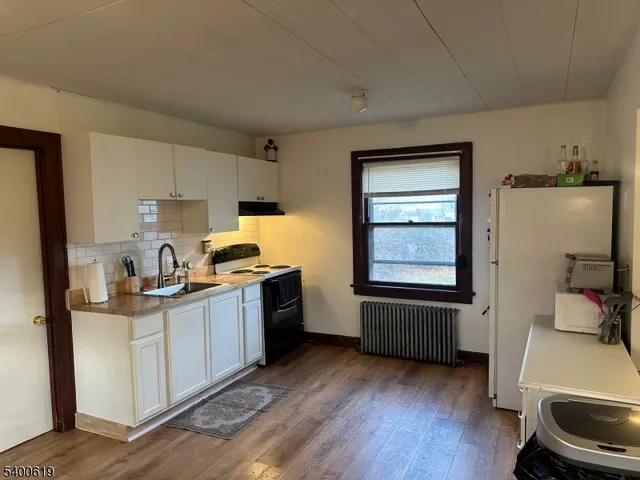 a kitchen with granite countertop a sink wooden floor and stainless steel appliances