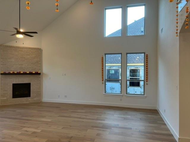 1407 Cartona Road Fate, TX 75087 - Photo 5 of 21 Vaulted ceiling living space with a brick fireplace, dark wood mantel, and wood-finish flooring