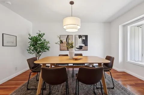 a dining room with furniture potted plants and wooden floor