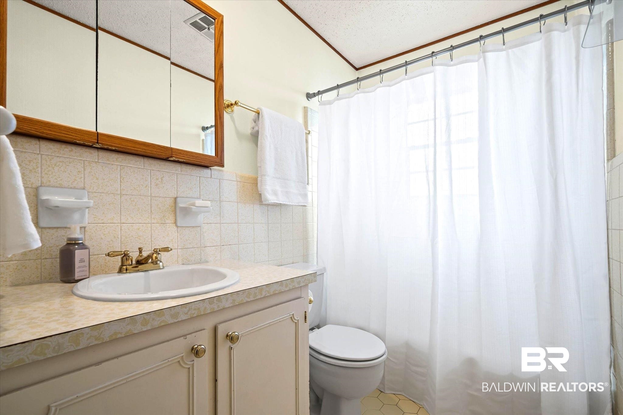 8090 Murray Hill Road Irvington, AL 36544 - Photo 25 of 40 Full bath with vanity, shower / bath combination with curtain, a textured ceiling, tile walls, and backsplash