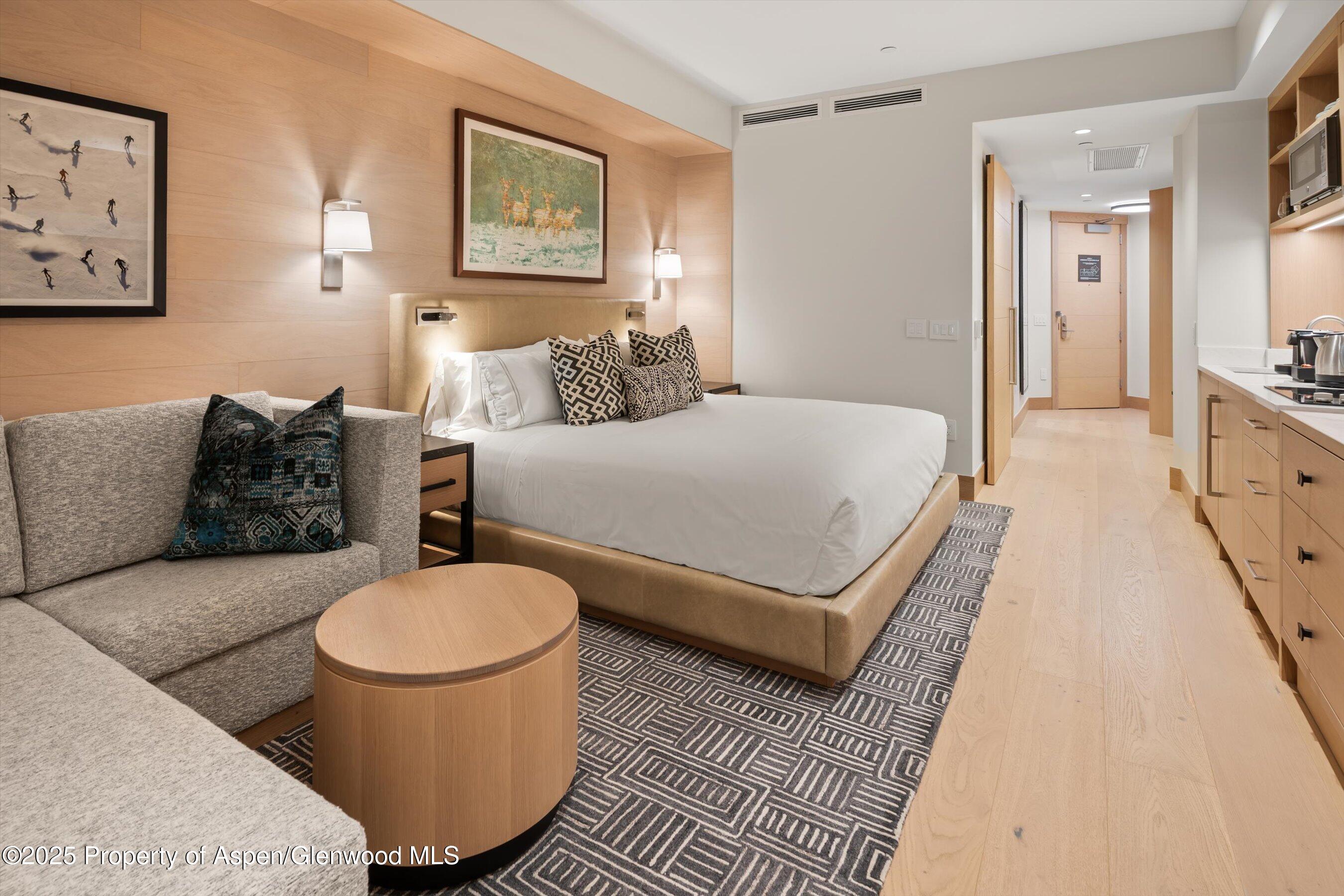 130 Wood Road, Unit 353355 Snowmass Village, CO 81615 - Photo 6 of 41 a spacious bedroom with a bed a couch and painting on the wall