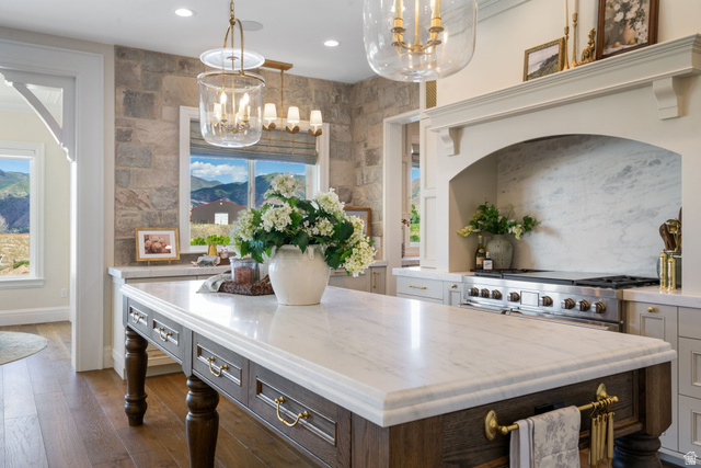115 East Hidden Ridge Lane, Unit 42 Mapleton, UT 84664 - Photo 10 of 103 Expansive kitchen island featuring a white countertop with a detailed edge, rich wood-finish cabinetry, and brass hardware