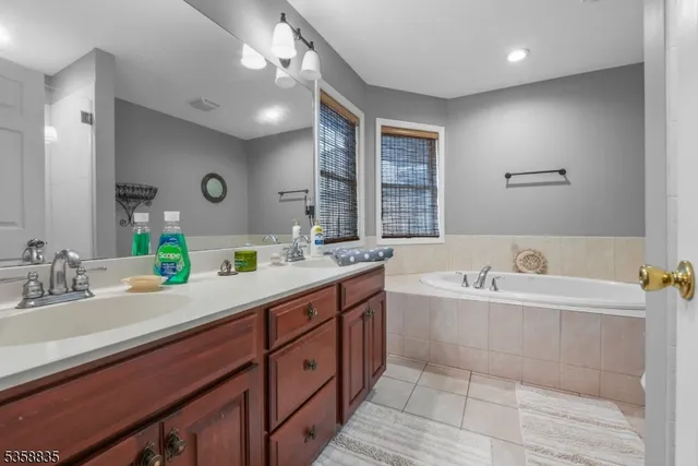 a spacious bathroom with a double vanity sink mirror and bathtub