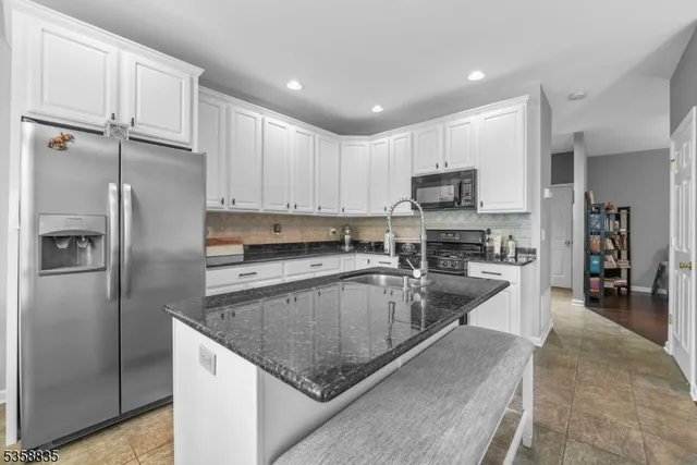 a kitchen with stainless steel appliances granite countertop a refrigerator a stove and a sink