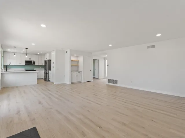 a view of a kitchen with a refrigerator and wooden floor