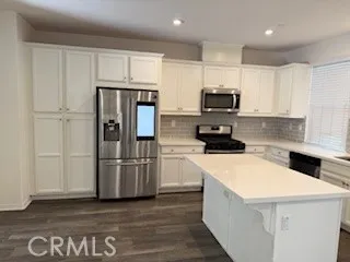 a kitchen with a refrigerator a stove top oven and wooden floor