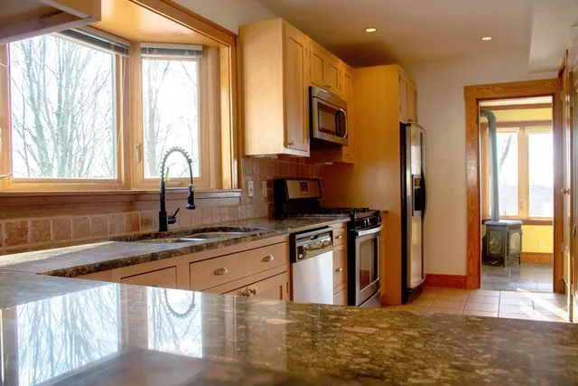 a large kitchen with stainless steel appliances granite countertop a stove and cabinets