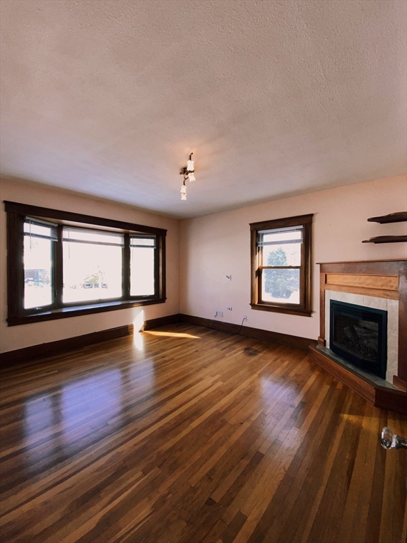 2-4 Sunset Hill Road Boston, MA 02132 - Photo 5 of 34 a view of empty room with wooden floor and fireplace