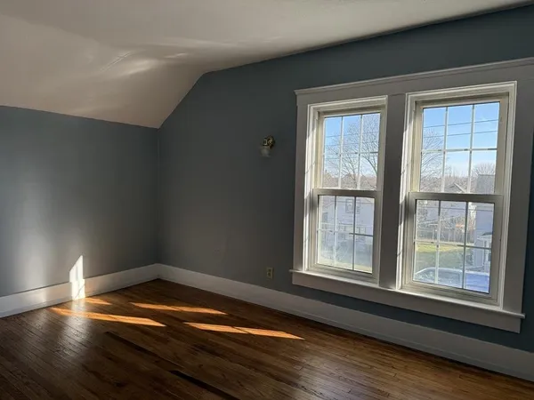 a view of an empty room with wooden floor and closet