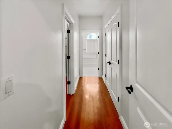 a view of a hallway with wooden floor and a bathroom