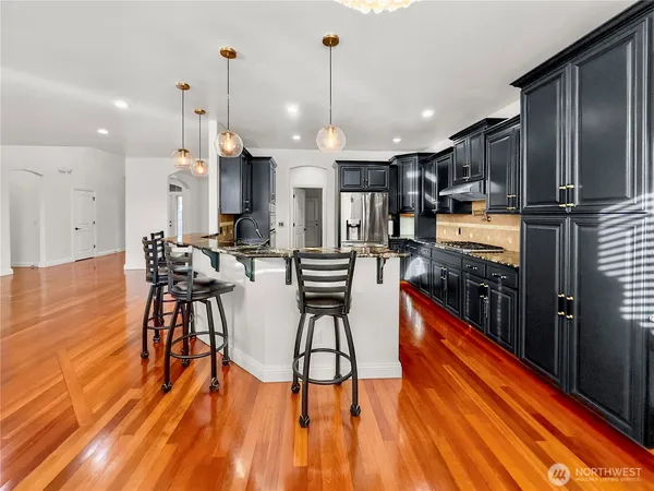 an open kitchen with wooden floor and stainless steel appliances