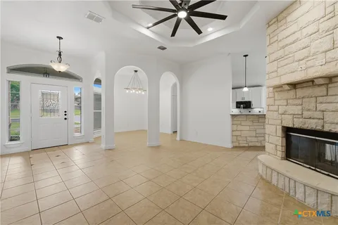 a view of a livingroom with a fireplace a chandelier fan and wooden floor
