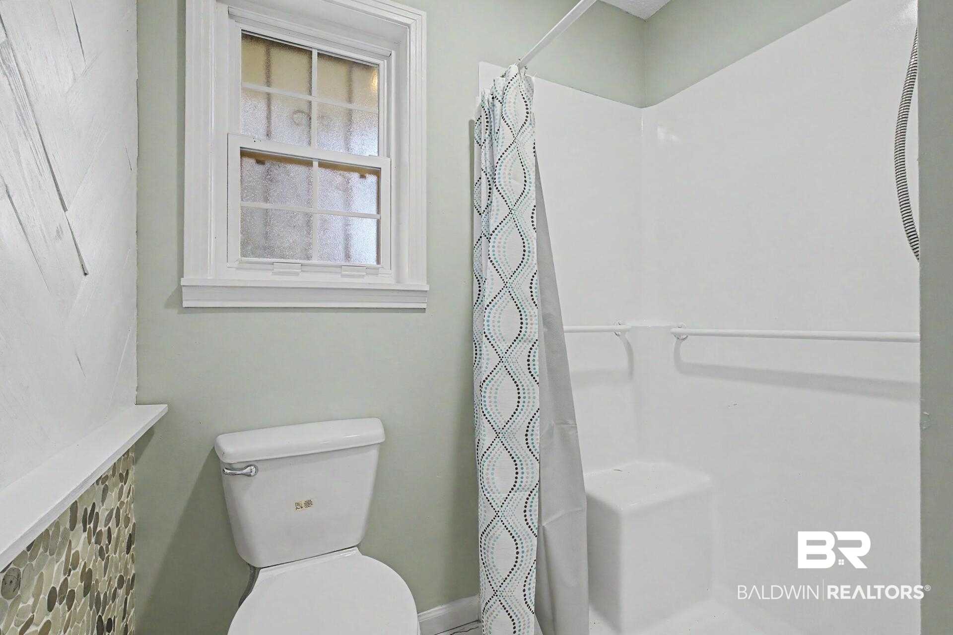 3791 Robinsonville Road Atmore, AL 36502 - Photo 46 of 47 Bathroom featuring a white toilet, mosaic tile wainscoting, white window trim, and a white shower stall with an integrated bench seat