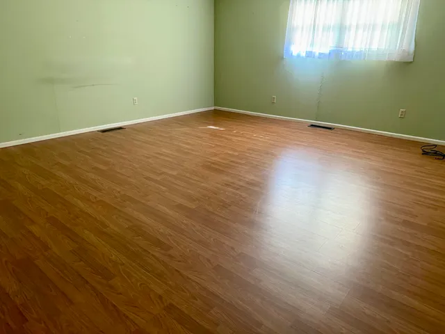 an empty room with wooden floor and a window